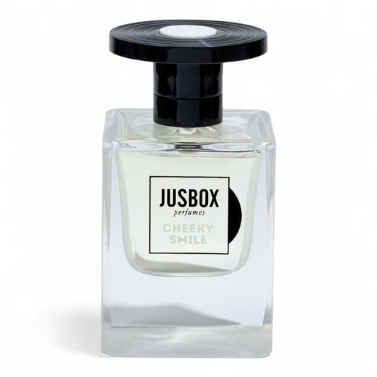 A sample of Jusbox Cheeky Smile, a modern ambery-woody scent built on Iso E Super, Ambroxan, and Cashmeran, available in decants and testers.