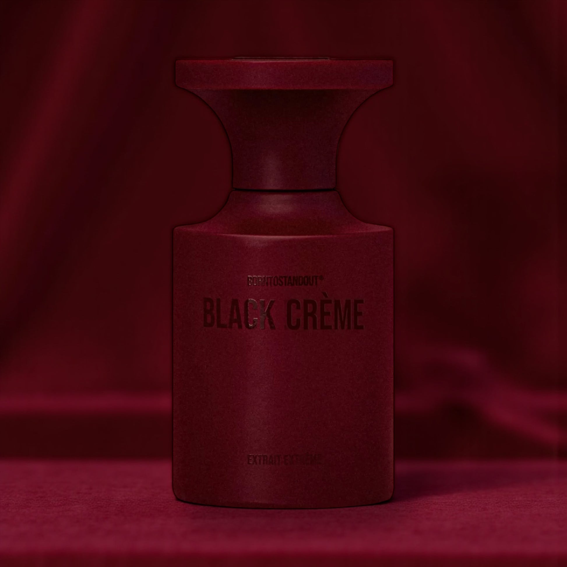 BORNTOSTANDOUT Black Crème perfume bottle styled in a dark dimly lit burgundy velvet background