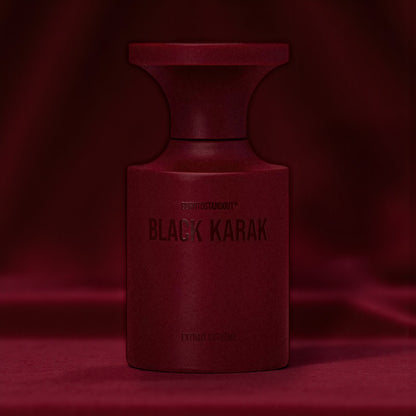 BORNTOSTANDOUT Black Karak perfume bottle styled in a dark dimly lit burgundy velvet background