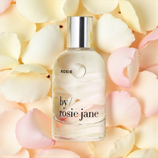 By Rosie Jane Rosie perfume sample – soft rose and white musk notes styled in a minimal rose petal setting.