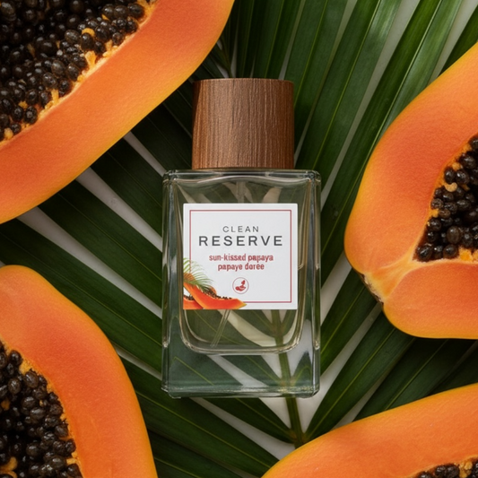 Clean Reserve Sun-Kissed Papaya styled with ripe papaya on a tropical palm leaf