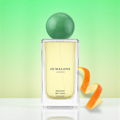Jo Malone Orange Bitters perfume sample – zesty orange and sandalwood notes styled in a warm amber-toned winter setting.
