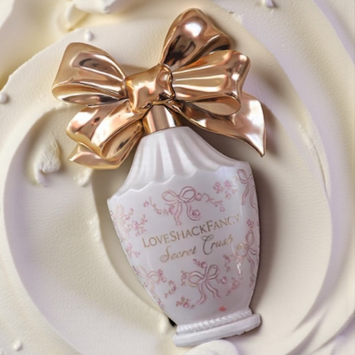LoveShackFancy Secret Crush perfume sample – whipped vanilla and champagne fragrance in a soft pastel setting.