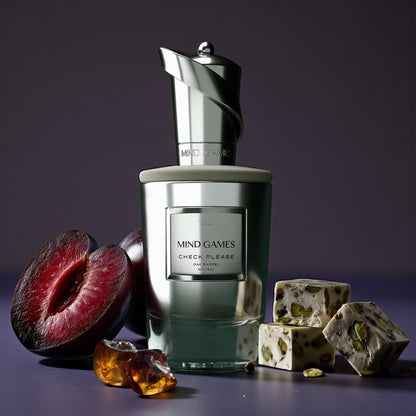 Mind Games Check Please perfume sample – apple cognac, plum, and vanilla bourbon notes styled in a warm amber-lit setting.