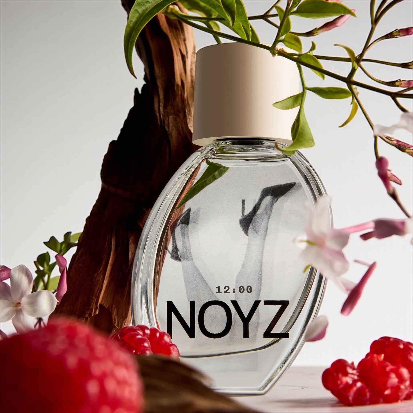 Noyz 12:00 perfume sample – spun sugar, raspberry, and warm wood notes styled in a golden, soft-lit setting.
