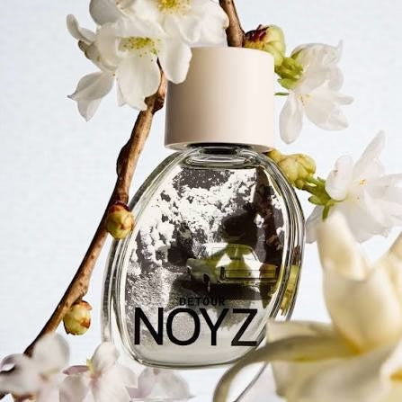 Noyz Detour perfume sample – jasmine, gardenia, and vanilla notes styled in a bright floral setting.
