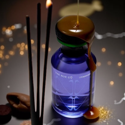 The Nue Co Otherwhere perfume sample – caramel, oud and incense notes styled in a minimal warm-toned setting.