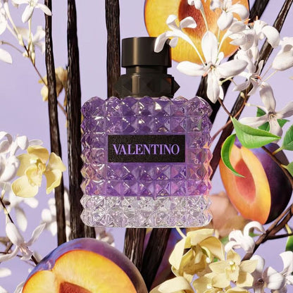 Valentino Donna Born In Roma Purple Melancholia perfume styled in a dark, elegant setting with plums and osmanthus flowers